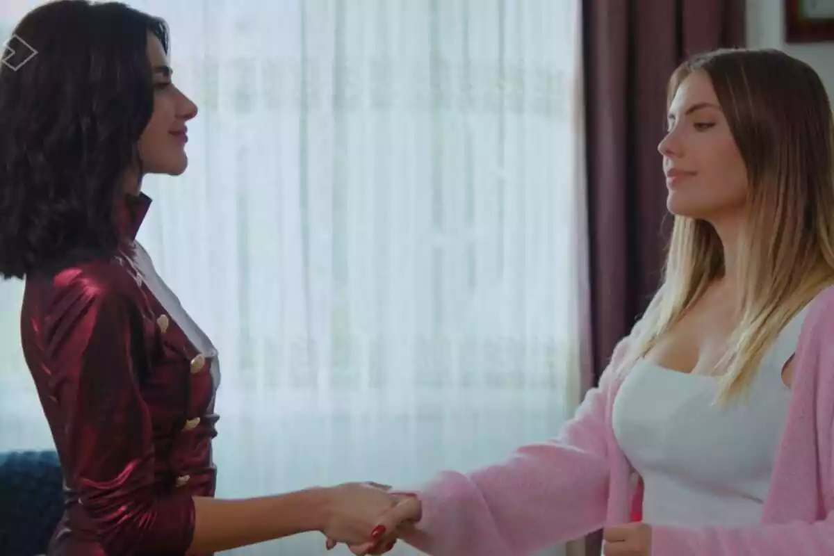 Captura de 'Pecado Original' amb Sahika amb un vestit vermell i Yildiz amb una samarreta blanca i jaqueta rosa donant-se la mà
